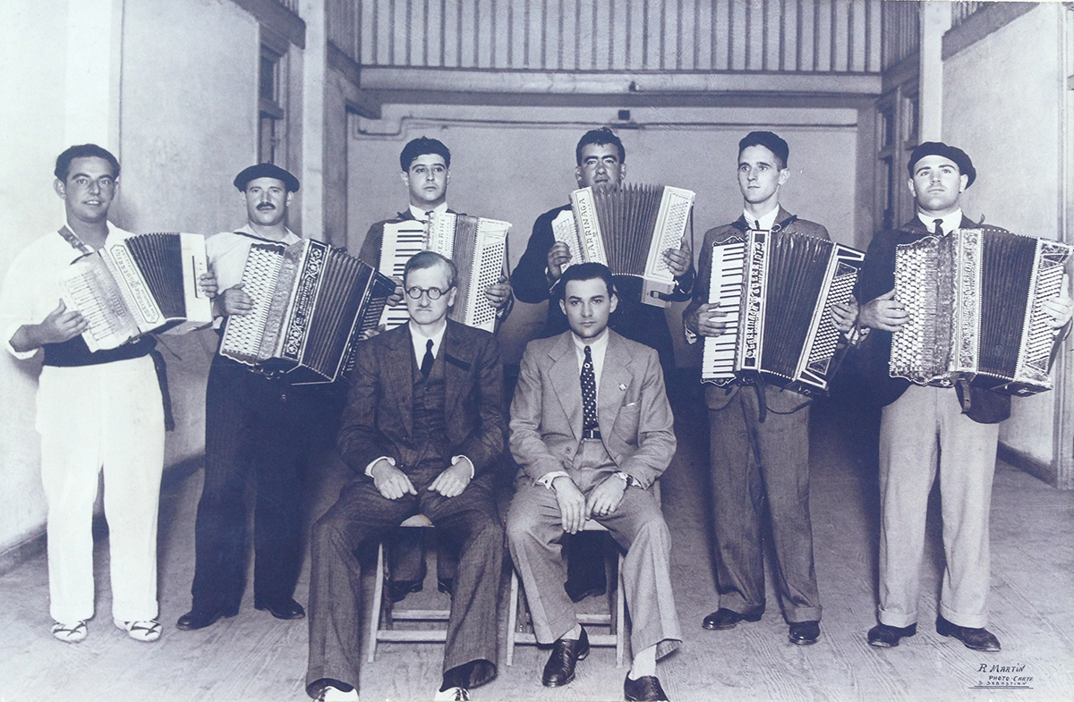 Akordeoi txapelketako finalistak, eta Larrinaga eta Guerrini jaunak eserita. Postala. Donostia, 1935. (Autorea: R. Martin. Aingeru Berguices bilduma)